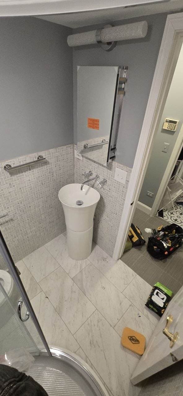 Pedestal sink bathroom remodel with marble-look tile floor and wall tile by BAX