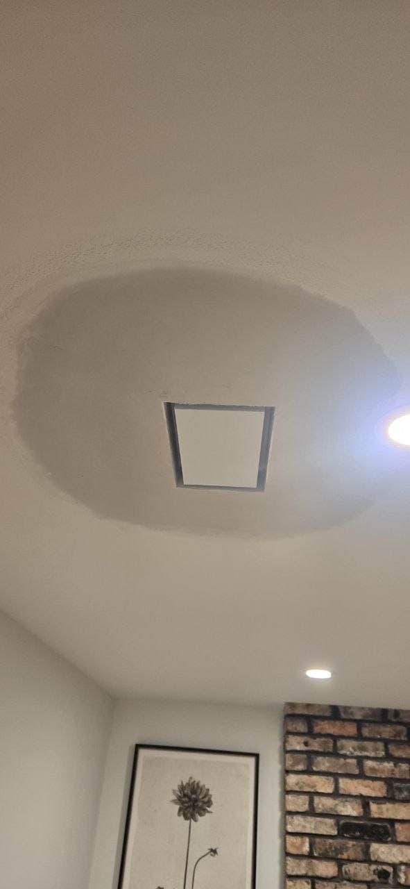 Ceiling drywall patch around an access panel after repair by BAX