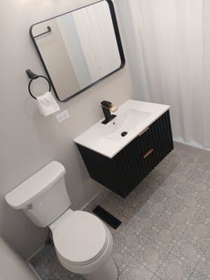 Completed compact bathroom with black vanity, mirror, and fixtures